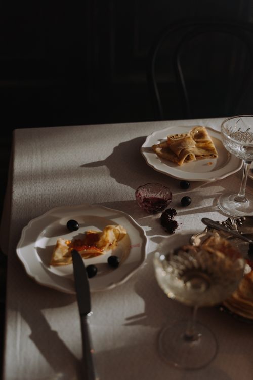 Free A dimly lit dining table with leftover dessert plates and elegant glassware. Stock Photo