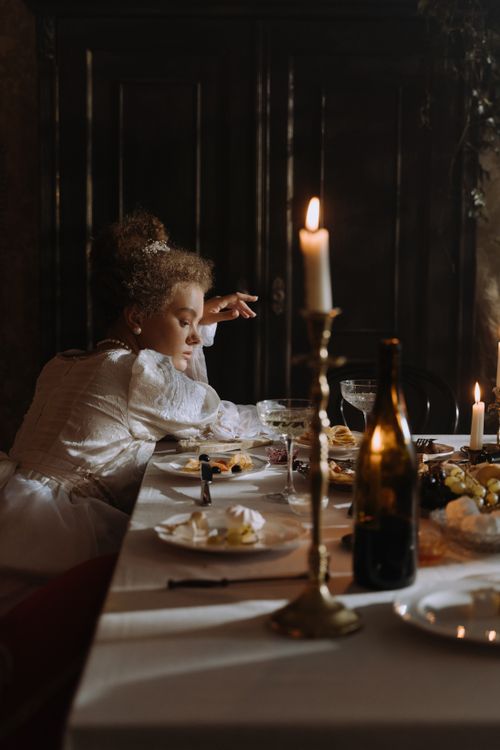Free Woman in period costume dining by candlelight, evoking an aristocratic atmosphere. Stock Photo