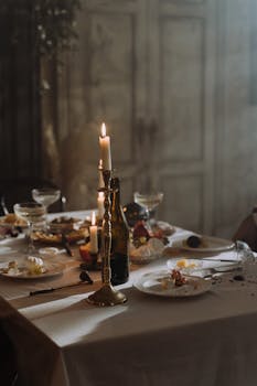 A dimly lit table set with leftover plates and candles, creating a cozy atmosphere.
