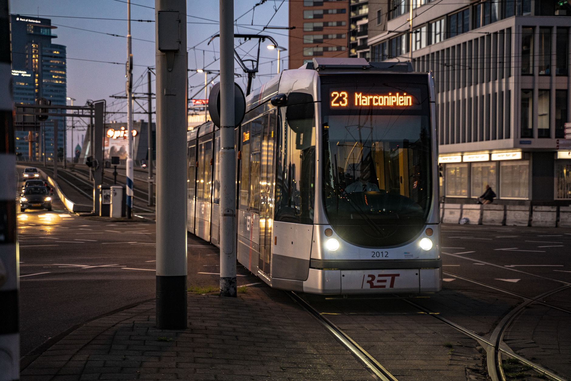 City tram number 23 towards Marconiplein navigating through urban streets during evening in a bustling downtown area.