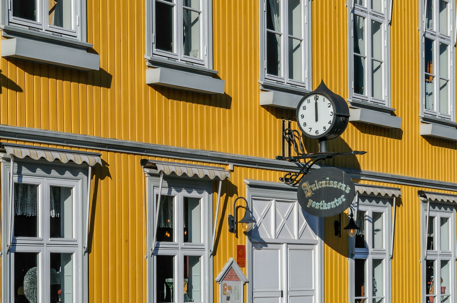 Charming yellow building facade with vintage clock and traditional windows on a sunny day.