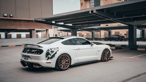 Free White Ford Mustang with Wolf Sticker Parked Near Building Stock Photo