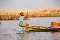 A young boy paddles a canoe in the serene waters of Ganvié, Benin, showcasing traditional fishing methods.