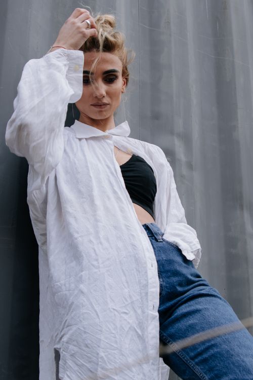 Free Fashionable young woman posing in a casual white shirt and jeans against a textured background. Stock Photo