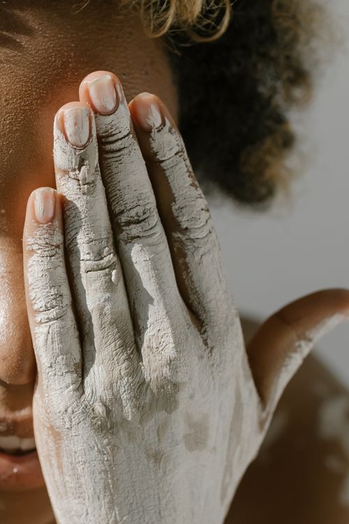 Free Close-up of a person with clay-covered hand on face, conveying creativity and expression. Stock Photo