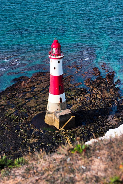 White and Red Lighthouse on the Brown Rocky Shore