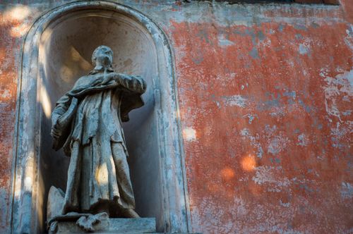 Free A weathered stone sculpture set in a niche against a rustic wall capturing historical elegance. Stock Photo