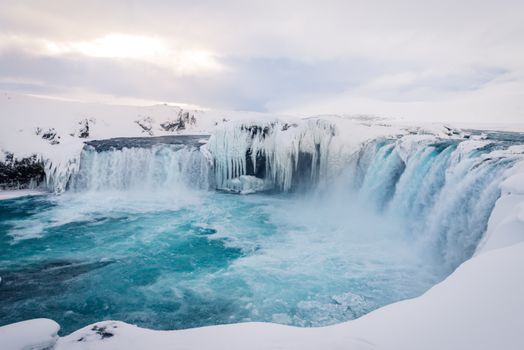 Breathtaking view of a frozen waterfall surrounded by snow-covered landscapes in winter.