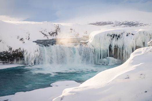 Breathtaking view of a frozen waterfall surrounded by snow in winter.