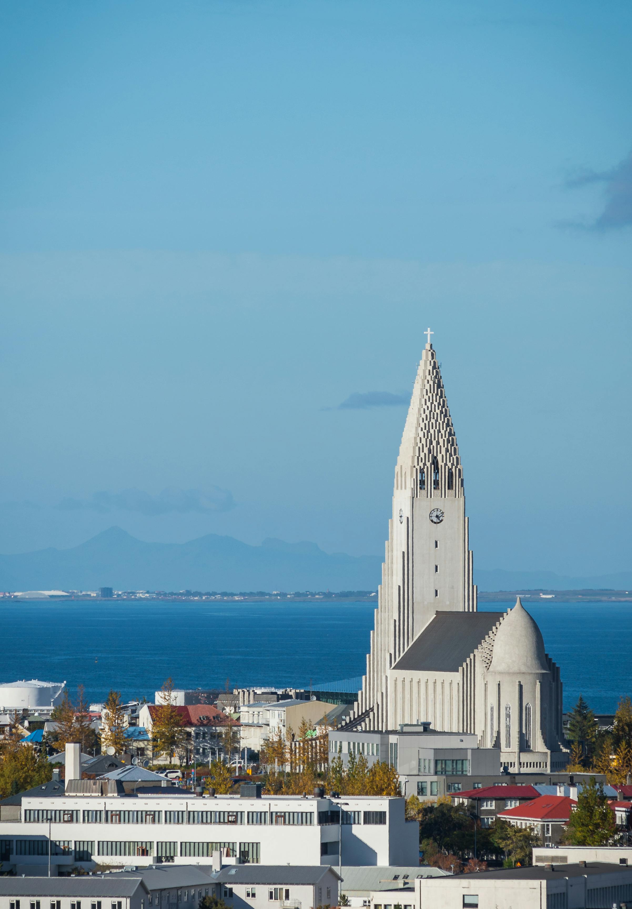 View of Hallgrimskirkja church in Reykjavik with a backdrop of ocean and mountains.