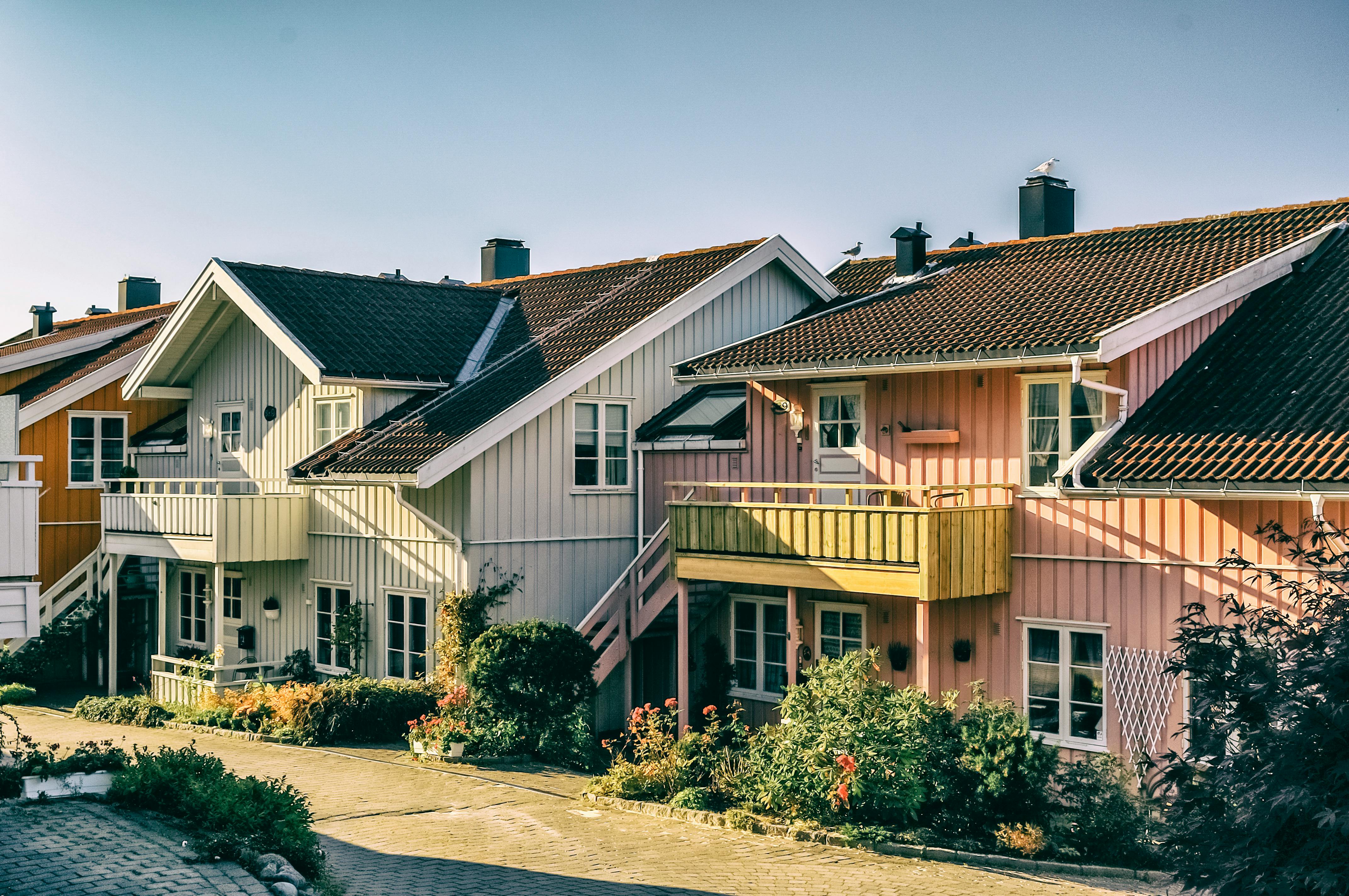 Beautiful pastel-colored Scandinavian houses with vibrant gardens in a sunny residential area.