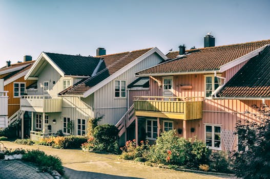 Beautiful pastel-colored Scandinavian houses with vibrant gardens in a sunny residential area.