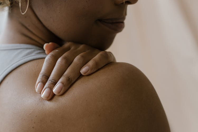 A Close-Up Shot Of A Woman Touching Her Shoulder