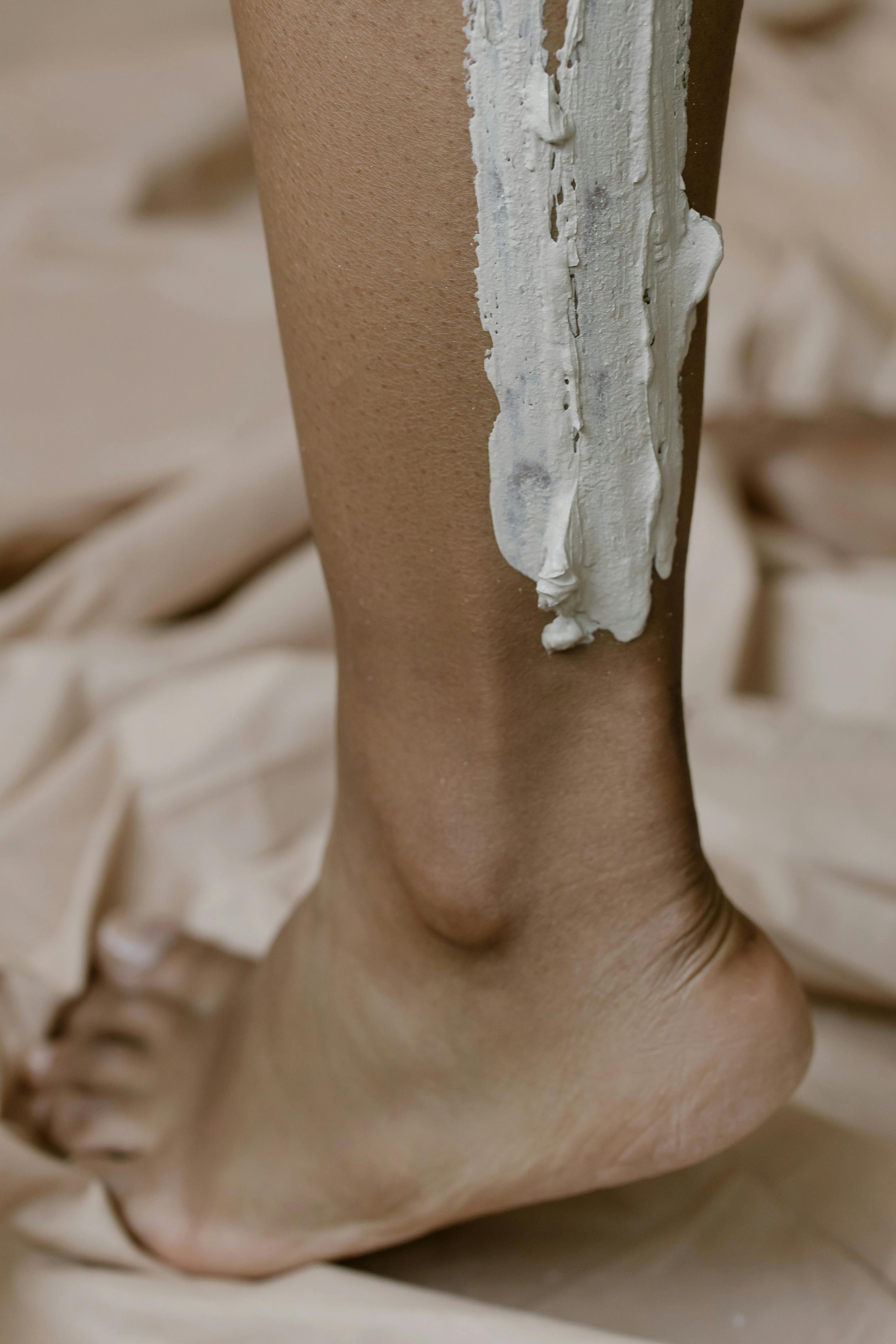 Detailed close-up of a leg with clay mask applied for skincare routine.