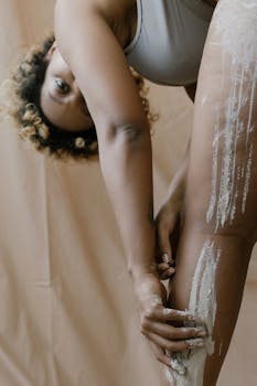 Close-up of a woman applying clay on her legs, focusing on skincare and self-care routines.