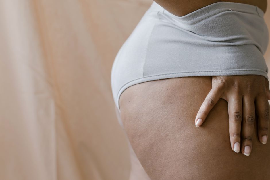 A close-up image of a woman's hand resting on her hip while wearing underwear, showing skin texture and subtle details.
