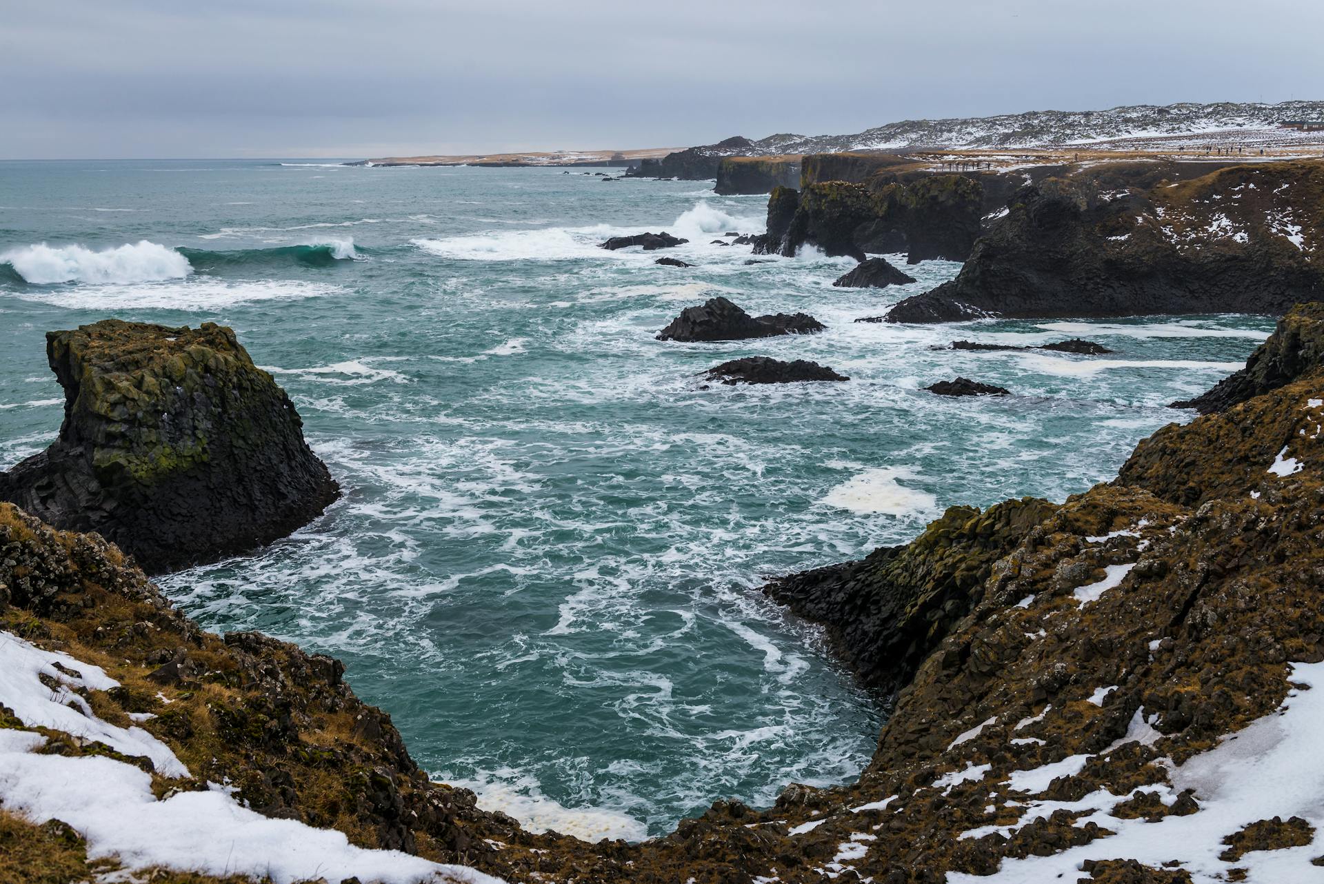 Explore the rugged coastline with dramatic waves and rocky cliffs, captured in a winter setting.