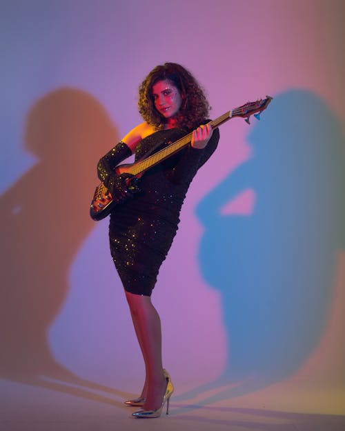 A Woman in a Dress Holding a Bass Guitar 