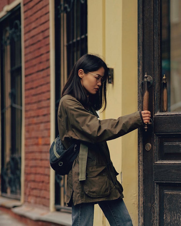 Calm Asian Woman Standing On Street And Opening Door Of Building