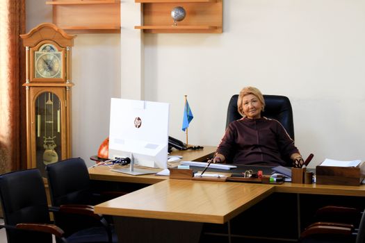 Businesswoman seated at a desk in a well-organized office environment, showcasing professionalism.