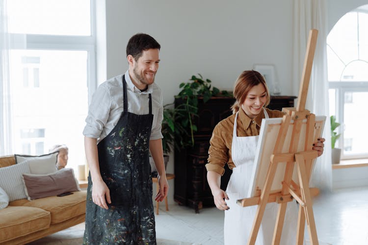 A Woman Holding A Canvas On A Wooden Easel Stand