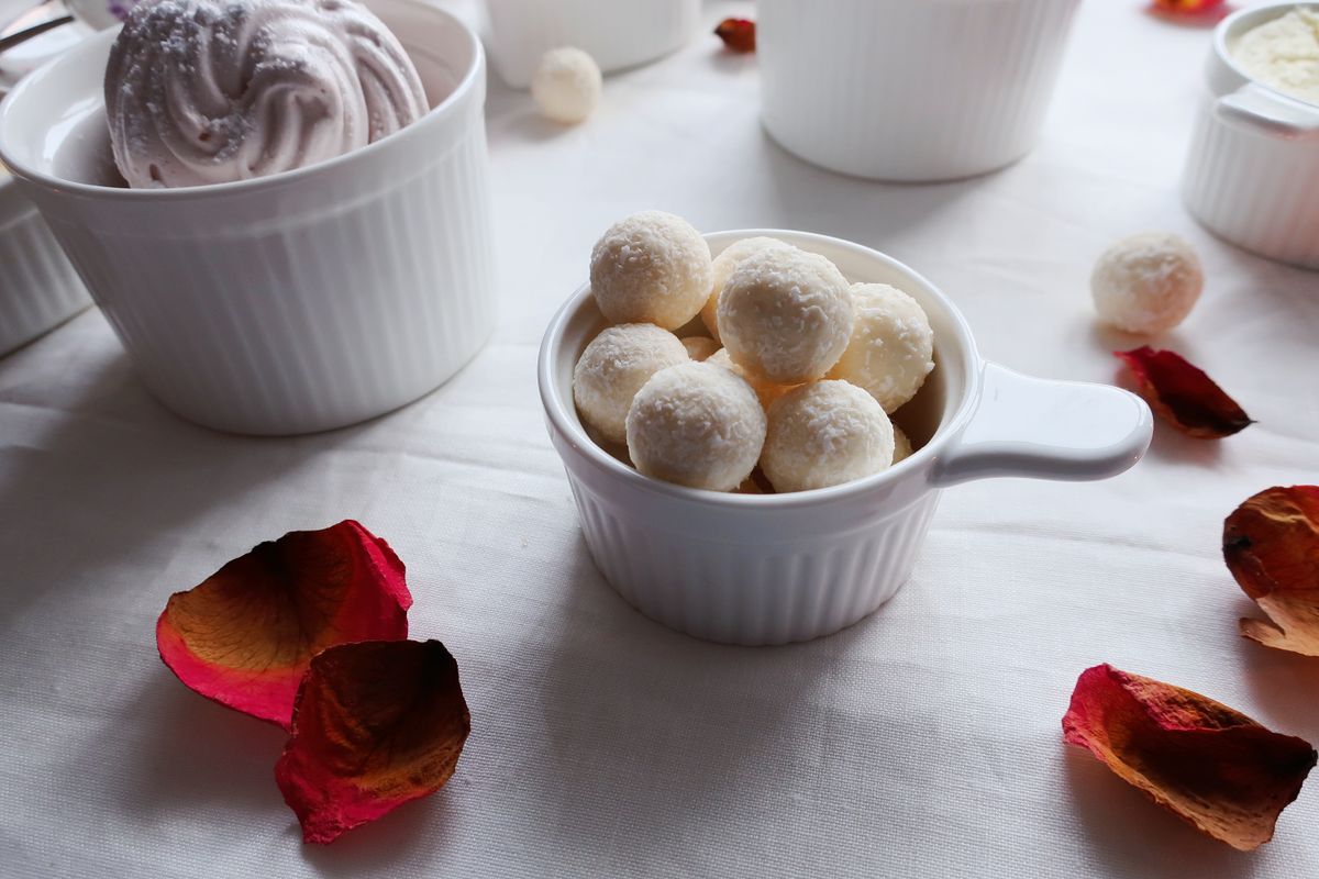 Close-up of coconut sweets in a white cup with ice cream and rose petals, perfect food photography.