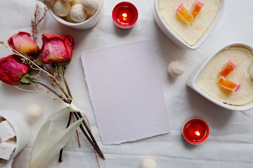 White Paper Beside Dry Red Roses