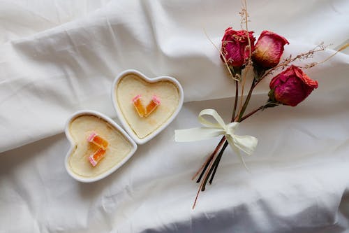 Red Roses Beside A White Heart Shaped Ceramic Plate