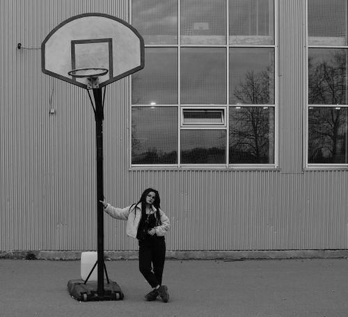 Free Black and white portrait of a woman leaning on a basketball hoop outdoors in Moscow. Stock Photo