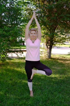 Adult woman performing tree yoga pose in a serene outdoor setting.