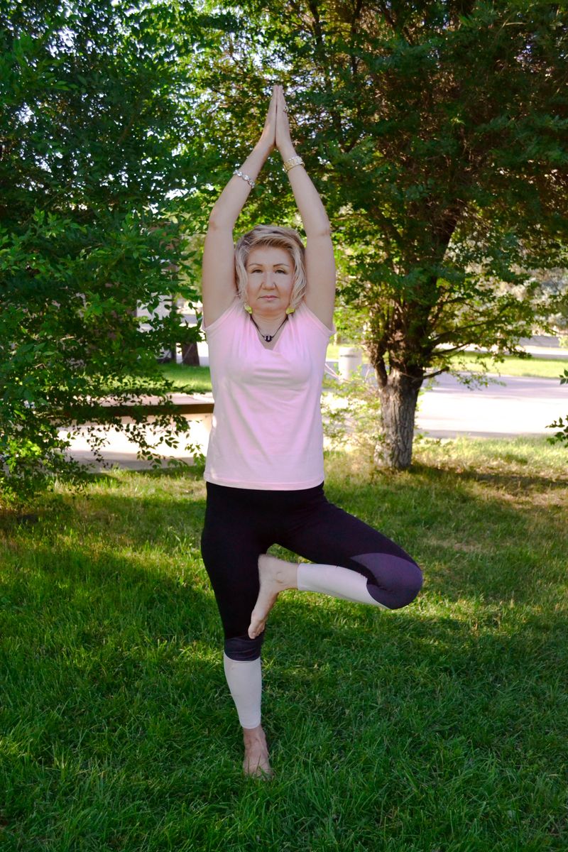 A woman practicing a yoga tree pose outdoors
