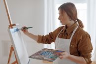Woman in Brown and White Long Sleeve Shirt Holding Pen