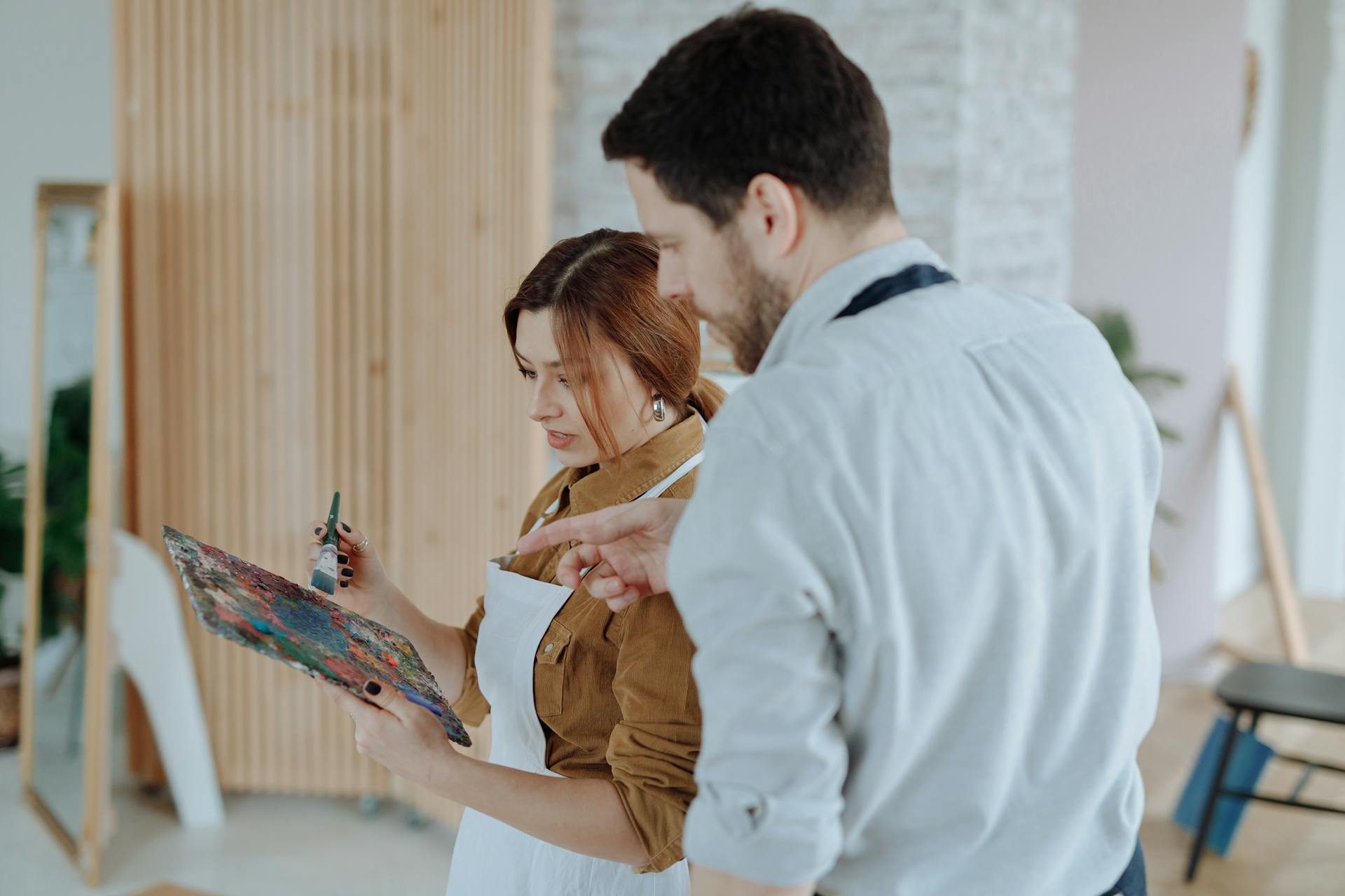 Man and woman collaborating in a creative indoor art lesson, using a color palette.