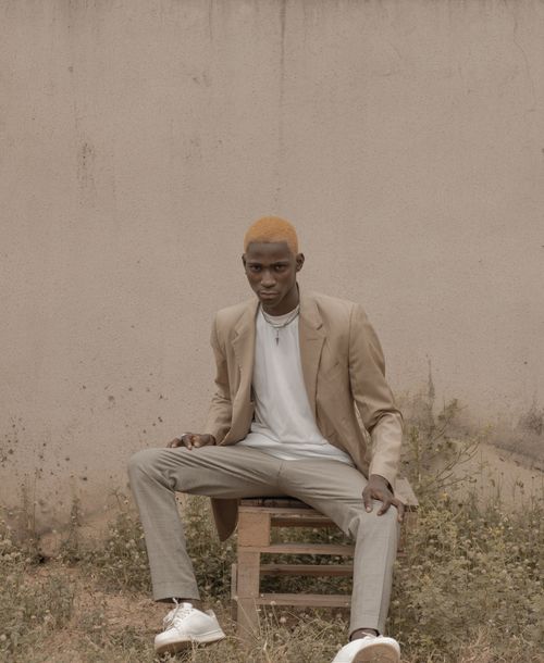 Free A fashionable man poses in casual attire outdoors against a rustic wall. Stock Photo