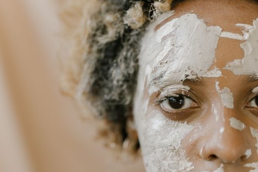 A detailed close-up photo of a person with a facial mud mask applied, focusing on their eye.