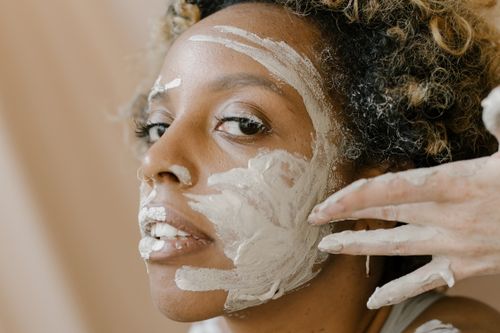 Free African woman applying a facial mask, emphasizing skincare beauty. Stock Photo