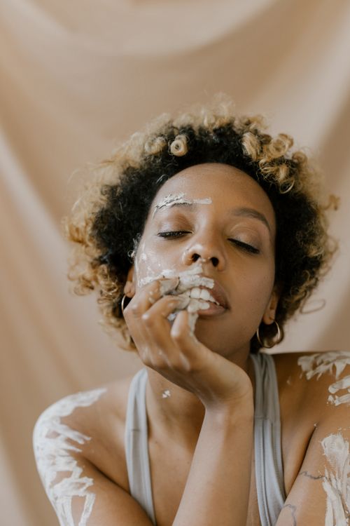 Free Artistic portrait of a woman with curly hair and face paint, featuring a serene expression. Stock Photo