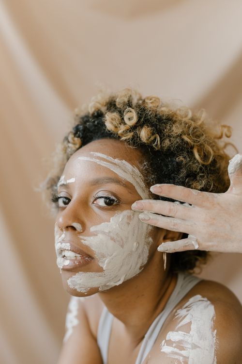 Free Close-up portrait of a woman with a clay mask during a skincare routine in a studio. Stock Photo