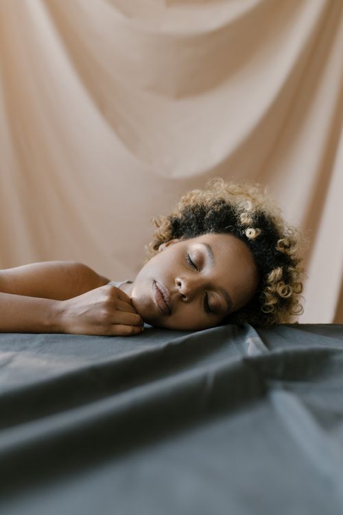 Free Close-up of a woman with curly hair peacefully sleeping on a table indoors. Stock Photo