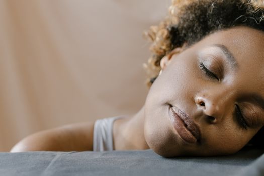 Peaceful close-up portrait of a woman with curly hair resting indoors.