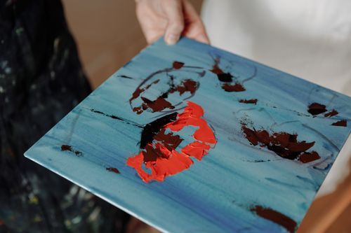 Free A person holding an abstract painting with bold knife paint strokes, featuring vibrant colors. Stock Photo