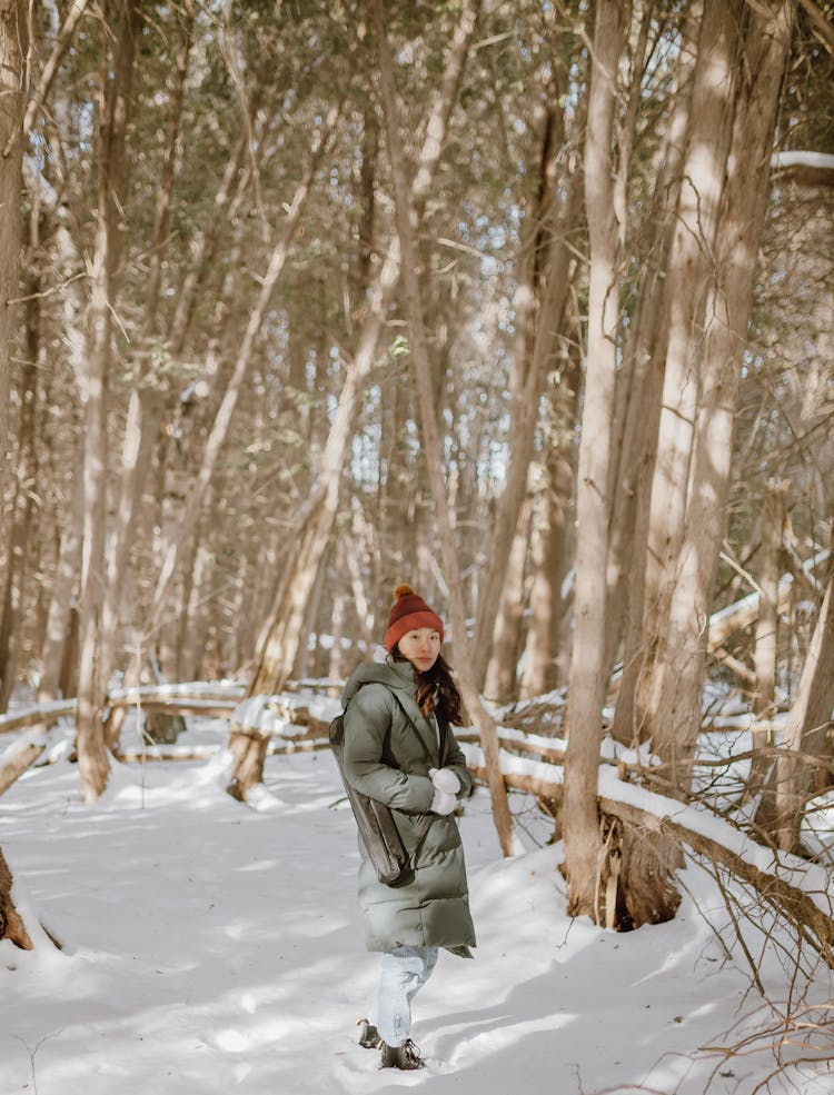 Stylish Young Ethnic Woman Standing In Winter Forest During Hiking Trip