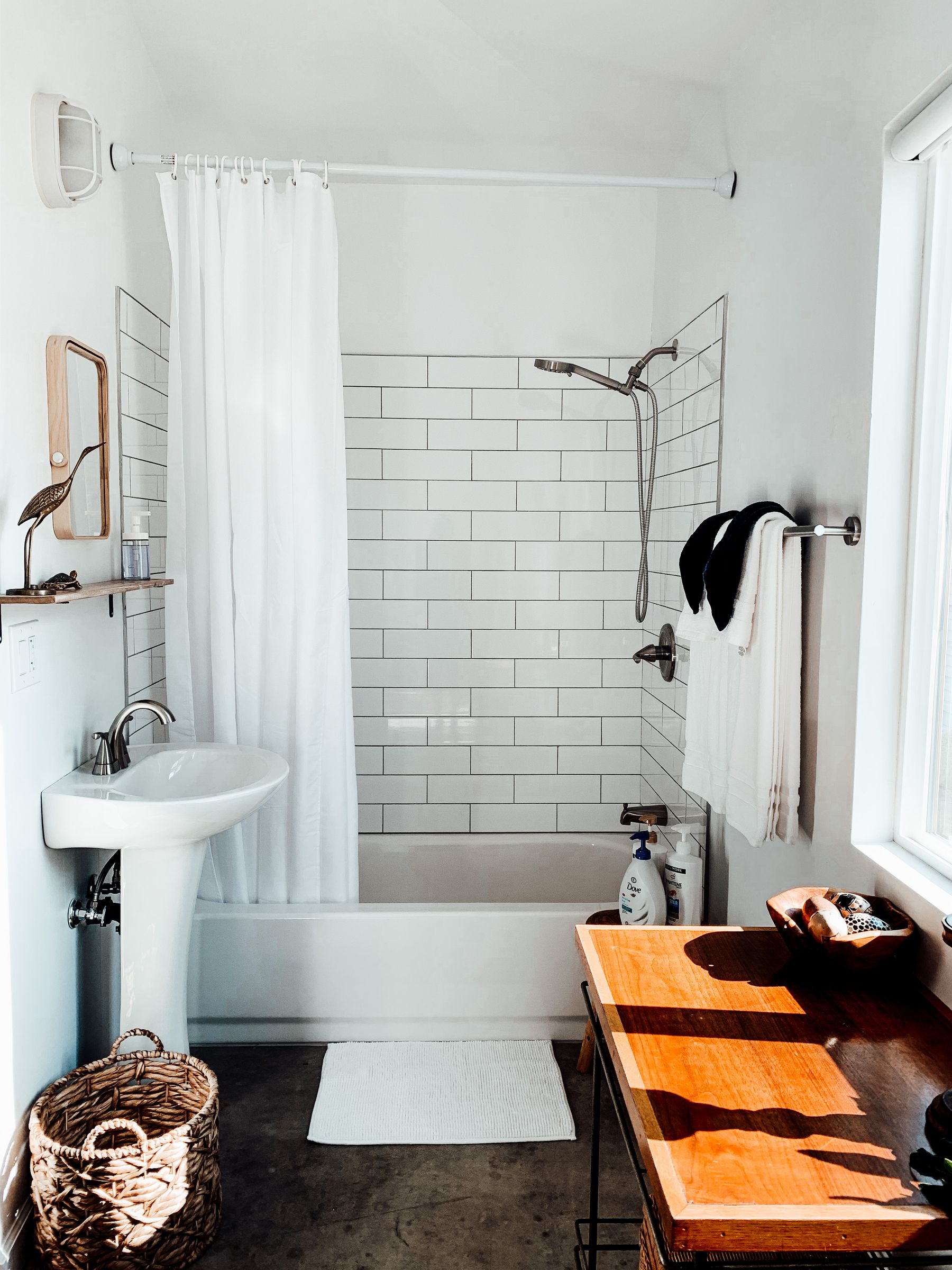 Bathroom with pedestal sink, white subway tile and warm light