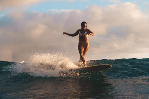 Photo of a Woman in a Bikini Surfing at the Beach