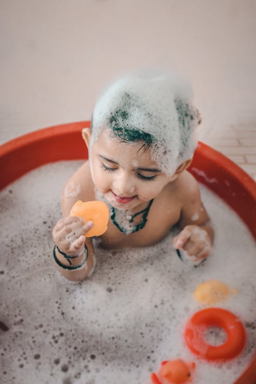 Close-Up Photo of an Adorable Child Playing while Taking a Bath