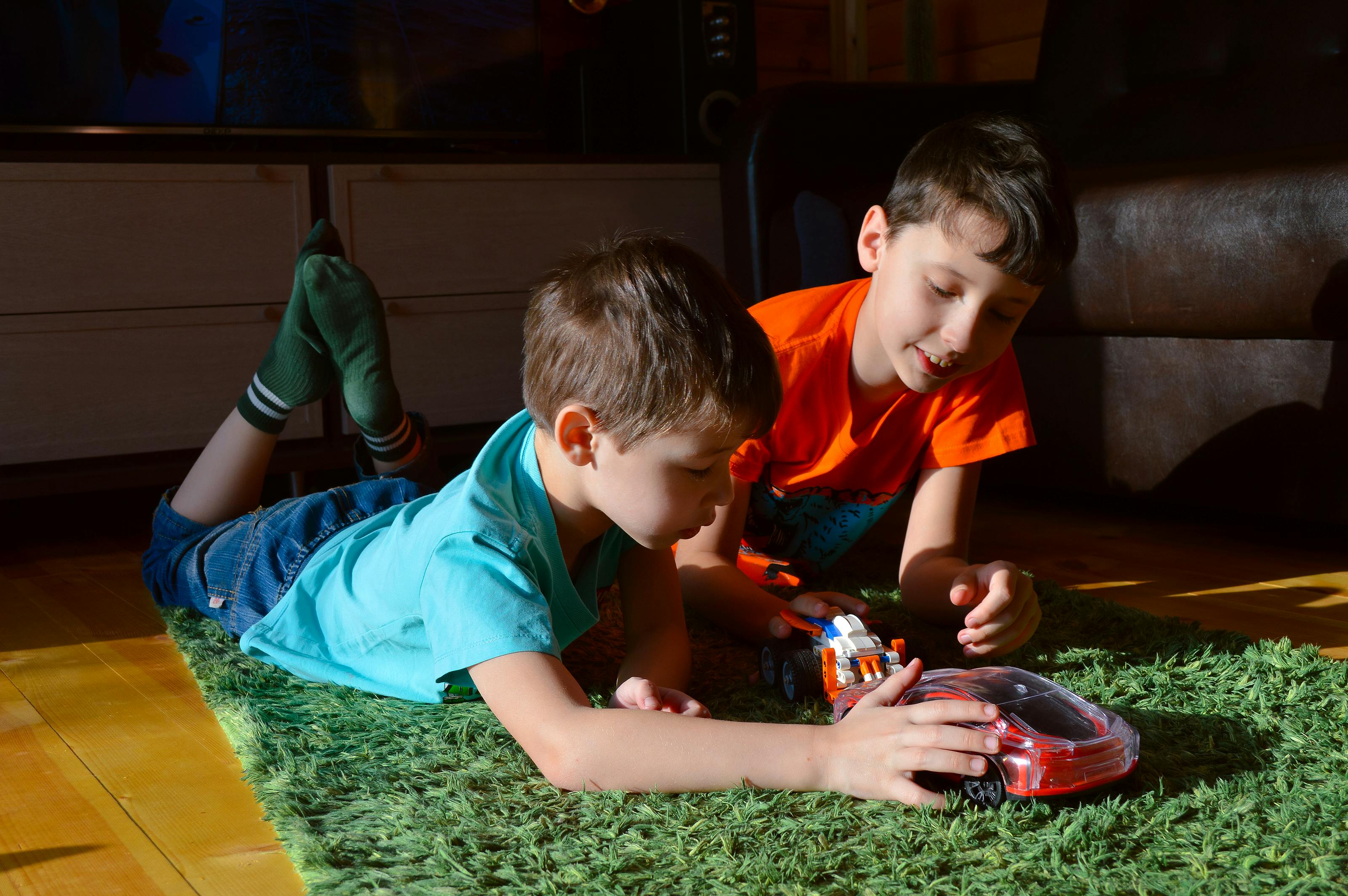 smiling boys playing with toy car on carpet at home