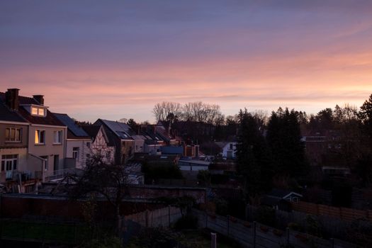 Tranquil village scene under a vibrant and dramatic sunset sky.