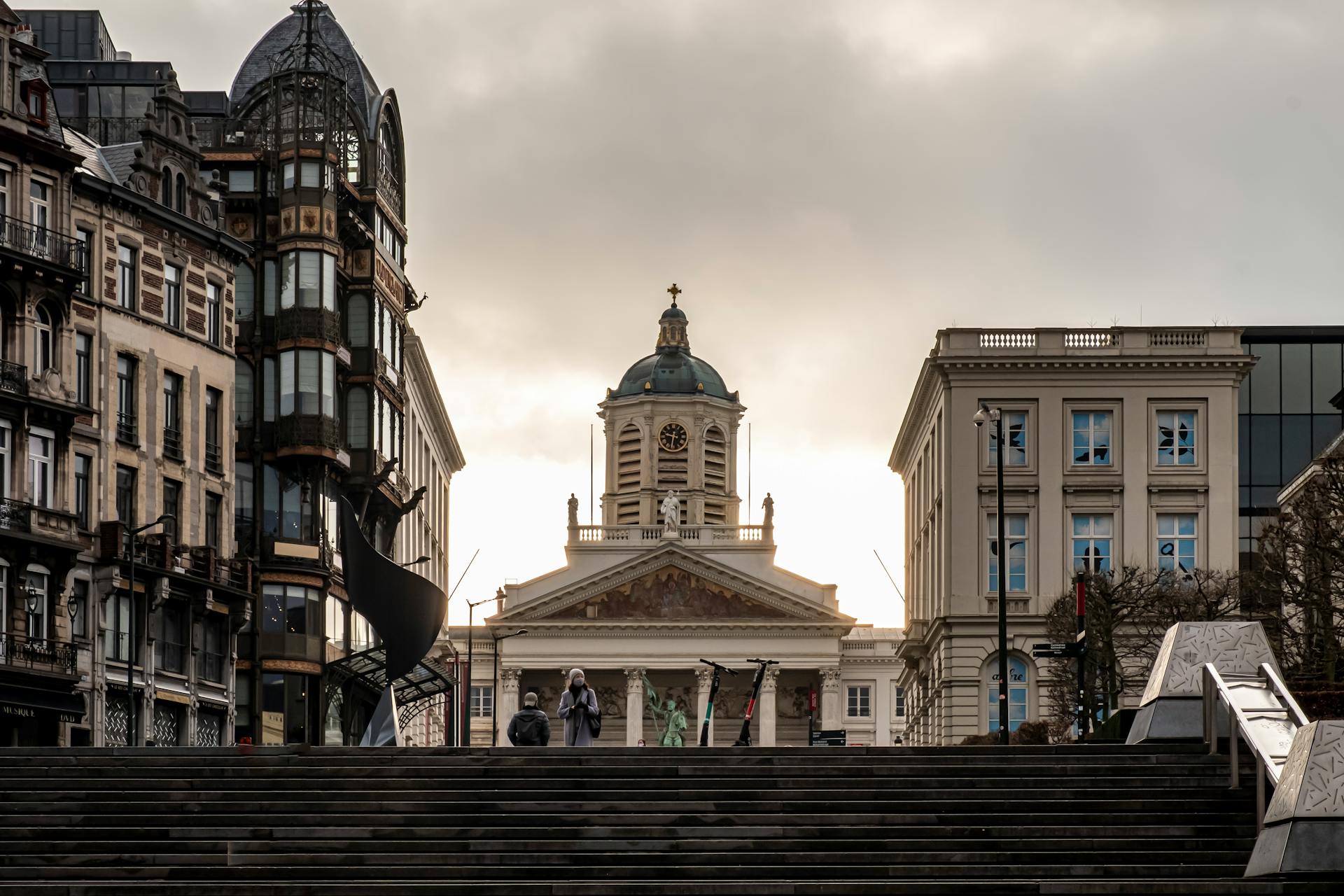 A Church Between City Buildings Under Gray Clouds