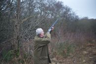 Man in Green Coat Holding Rifle