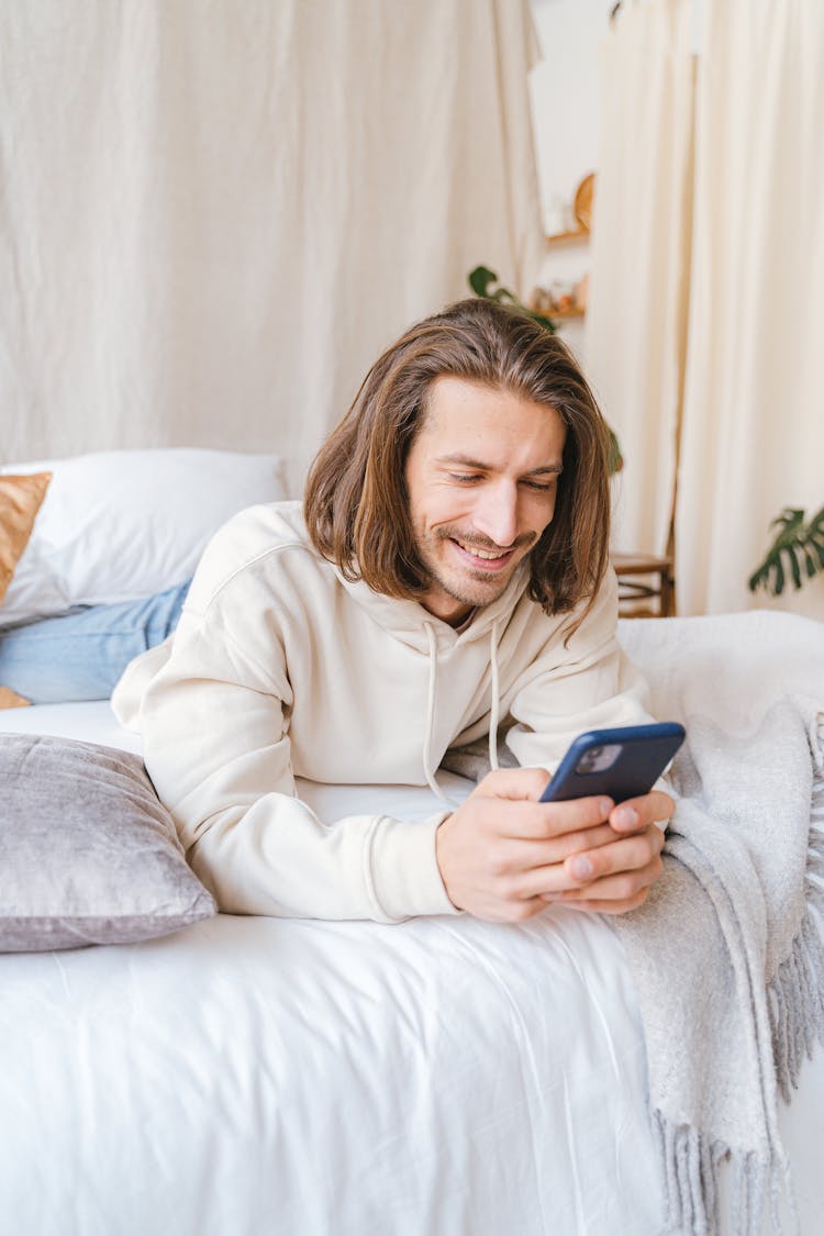 Smiling Man Texting On A Smartphone